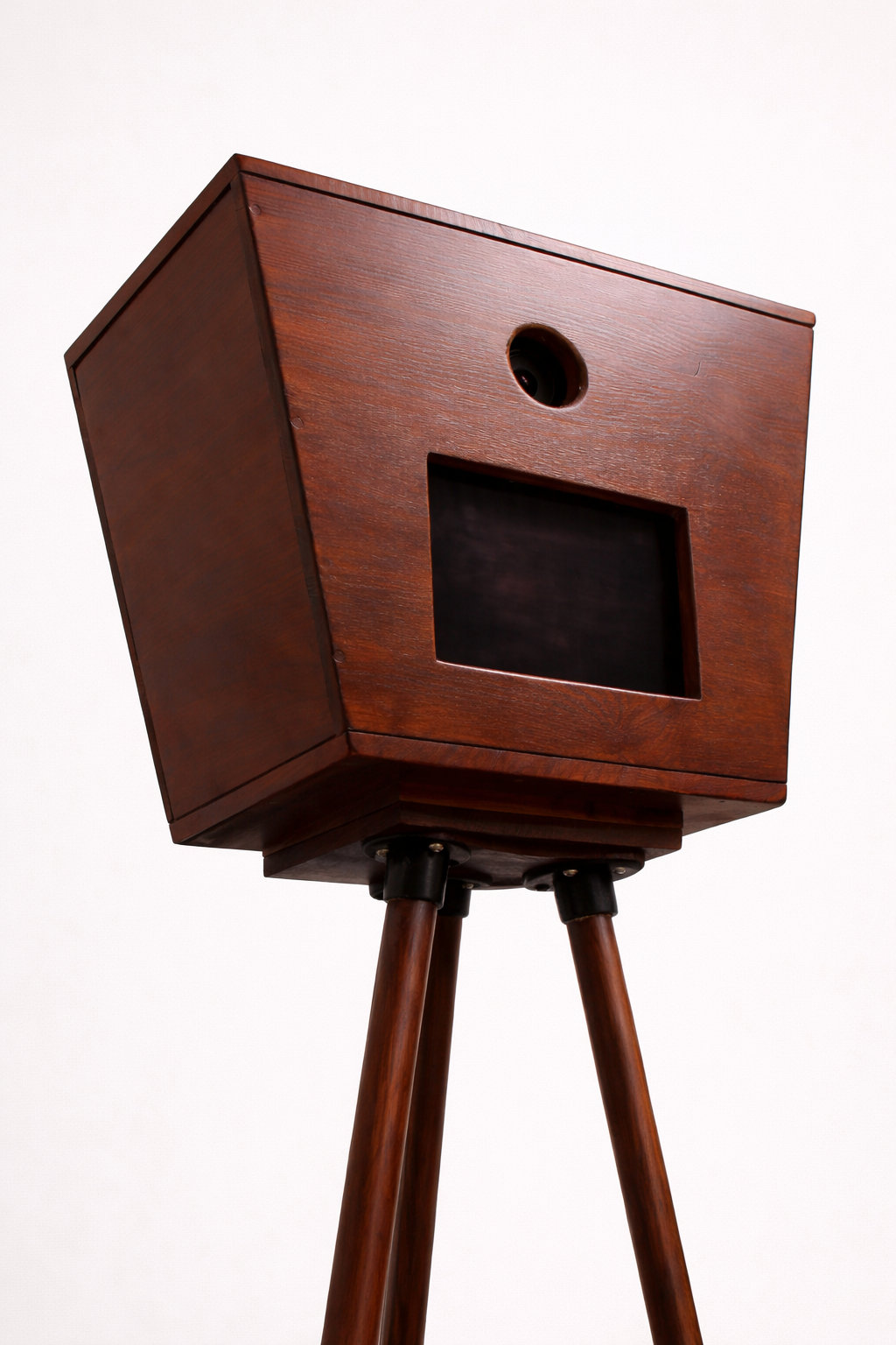 De Luxo Photobooth van Luxo heeft een premium cameradoos in vintage-stijl met een ronde lensopening en rechthoekige uitsparing, gemonteerd op een houten statief - een elegante photobooth voor elke bruiloft, afgebeeld tegen een witte achtergrond.